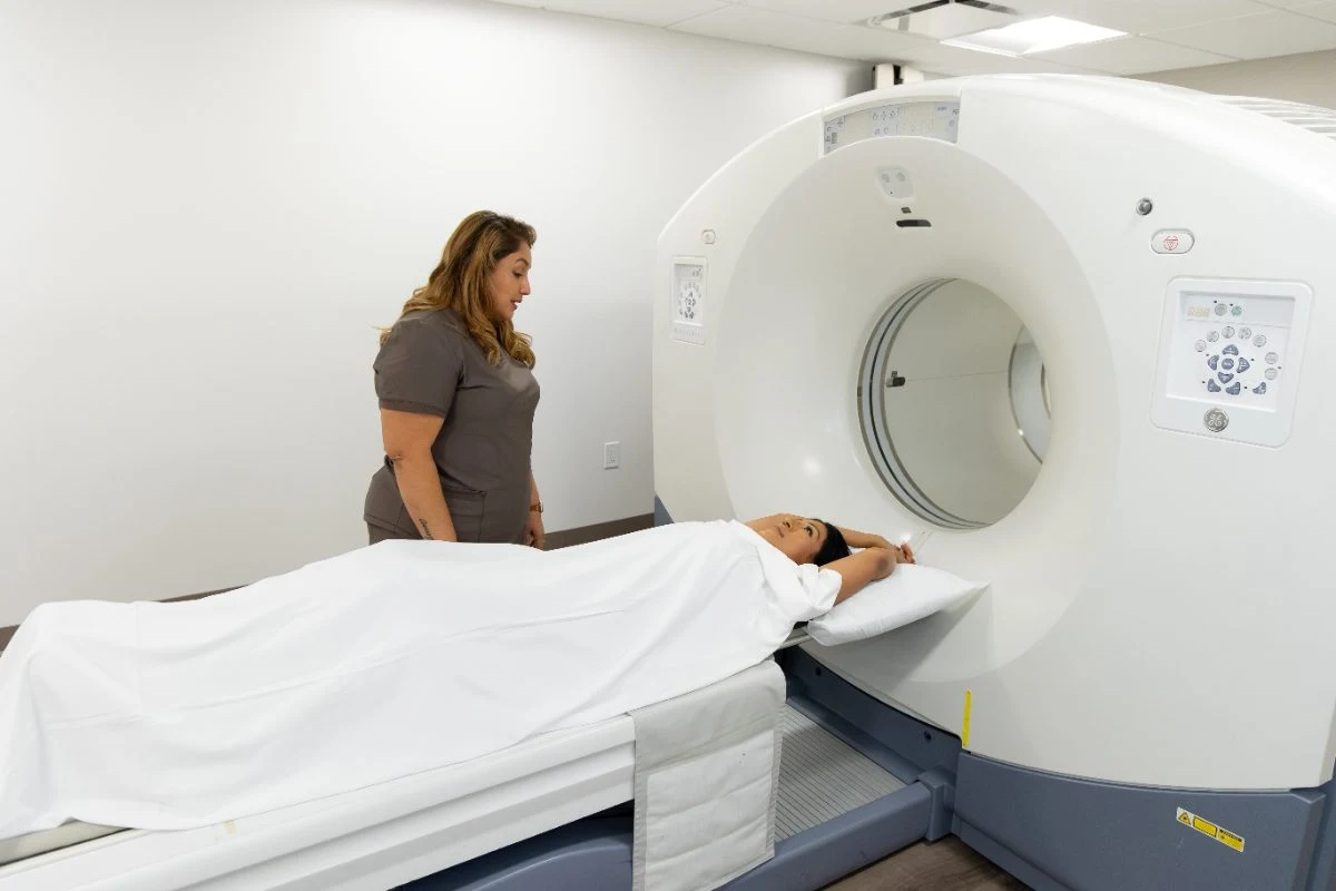 A technologist positioning a patient for a PET/CT scan at the Wellness Imaging Center